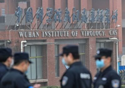 Some people wearing uniforms and masks standing near the Wuhan Institute of Virology