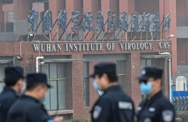 Some people wearing uniforms and masks standing near the Wuhan Institute of Virology