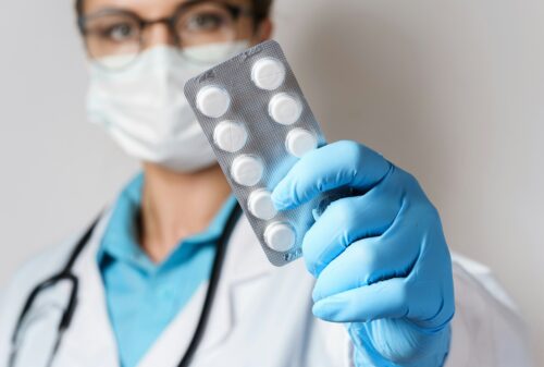 A physician holding out some pills