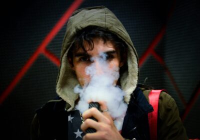 a boy vaping, the lower part of his face obscured by smoke