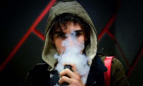a boy vaping, the lower part of his face obscured by smoke