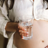 a pregnant woman with a glass of drinking water
