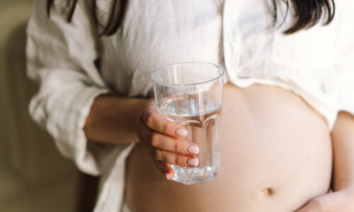 a pregnant woman with a glass of drinking water