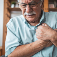 Close up photo of a man feeling a sharp pain in his chest