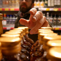 A man reaches out to get a bottle of liquor in a liquor store