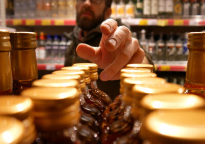 A man reaches out to get a bottle of liquor in a liquor store