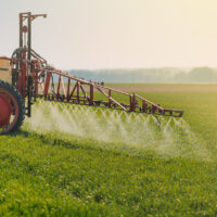 A tractor sprays herbicides on a field
