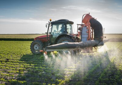 A tractor spraying pesticides on crops.