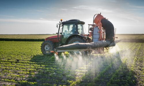 A tractor spraying pesticides on crops.