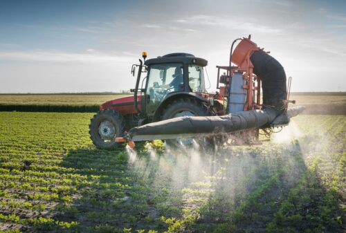 A tractor spraying pesticides on crops.