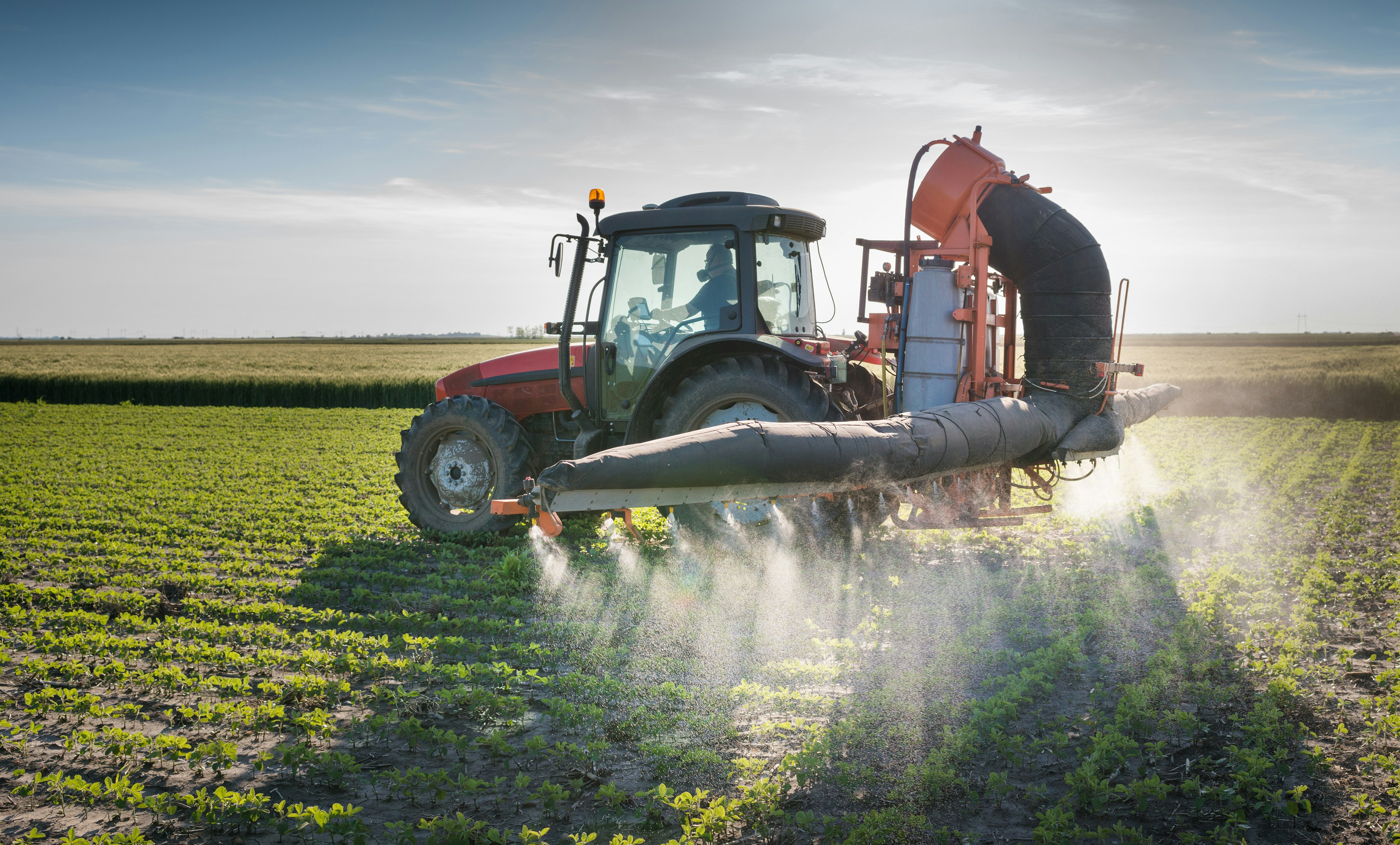 A tractor spraying pesticides on crops.