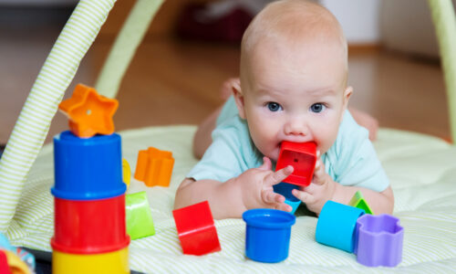 A baby with a plastic toy in their mouth