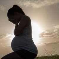 A pregnant woman with her face in her hands