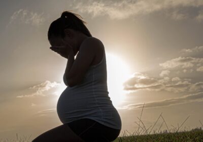 A pregnant woman with her face in her hands