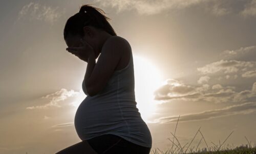 A pregnant woman with her face in her hands