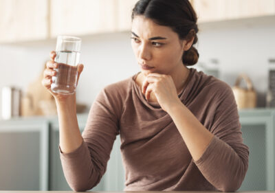 A woman holding and examining a glass of water