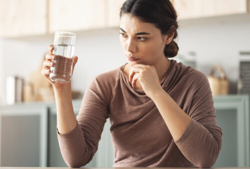 A woman holding and examining a glass of water