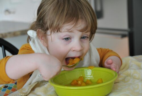 A small child eating canned peaches